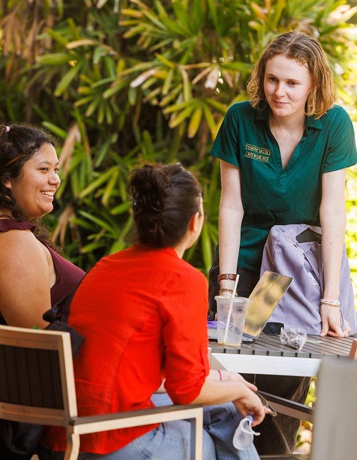 three students sit outside pit stop cafe 